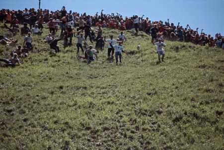 Competitors pursue a Double Gloucester cheese in the annual Cheese Rolling event at Cooper's Hill, Painswick, Gloucestershire, England.